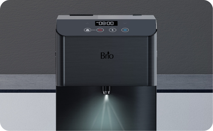 A close-up of a Brio water dispenser with digital display, control buttons, and a nozzle dispensing water illuminated by a light. The device is set against a gray background.